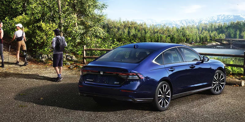 Two people walking away from a navy car.
