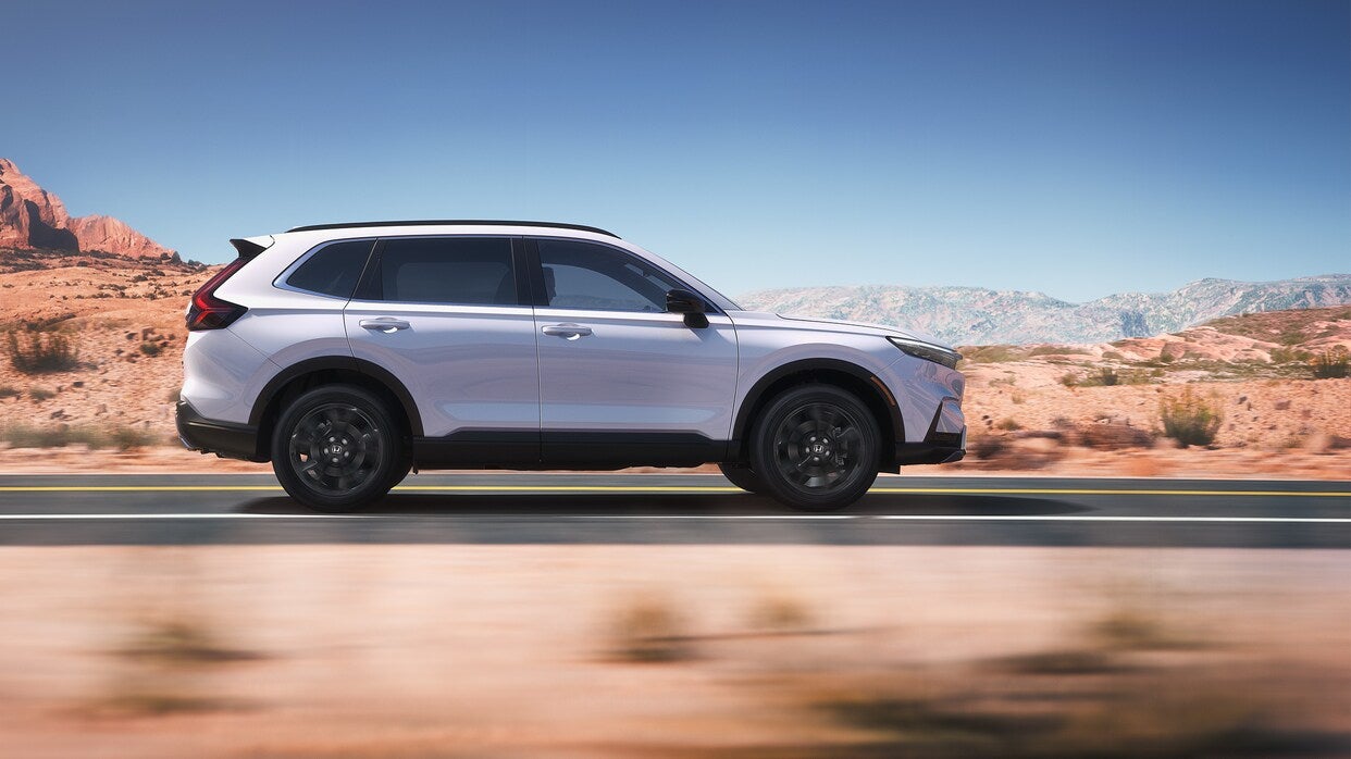 Side profile of the 2025 Honda CR-V driving through a desert landscape, highlighting its sleek design and performance