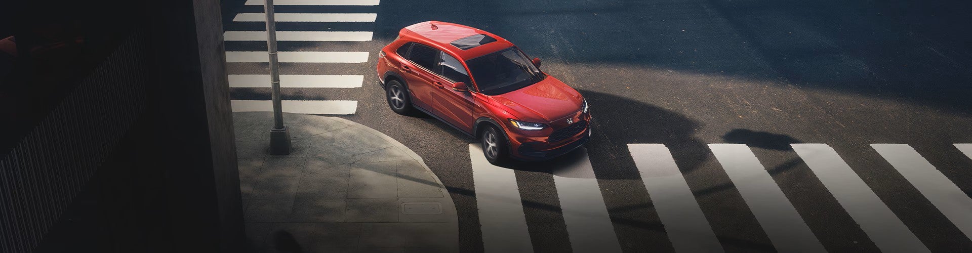 a red honda hr-v turning right in the city with crosswalks
