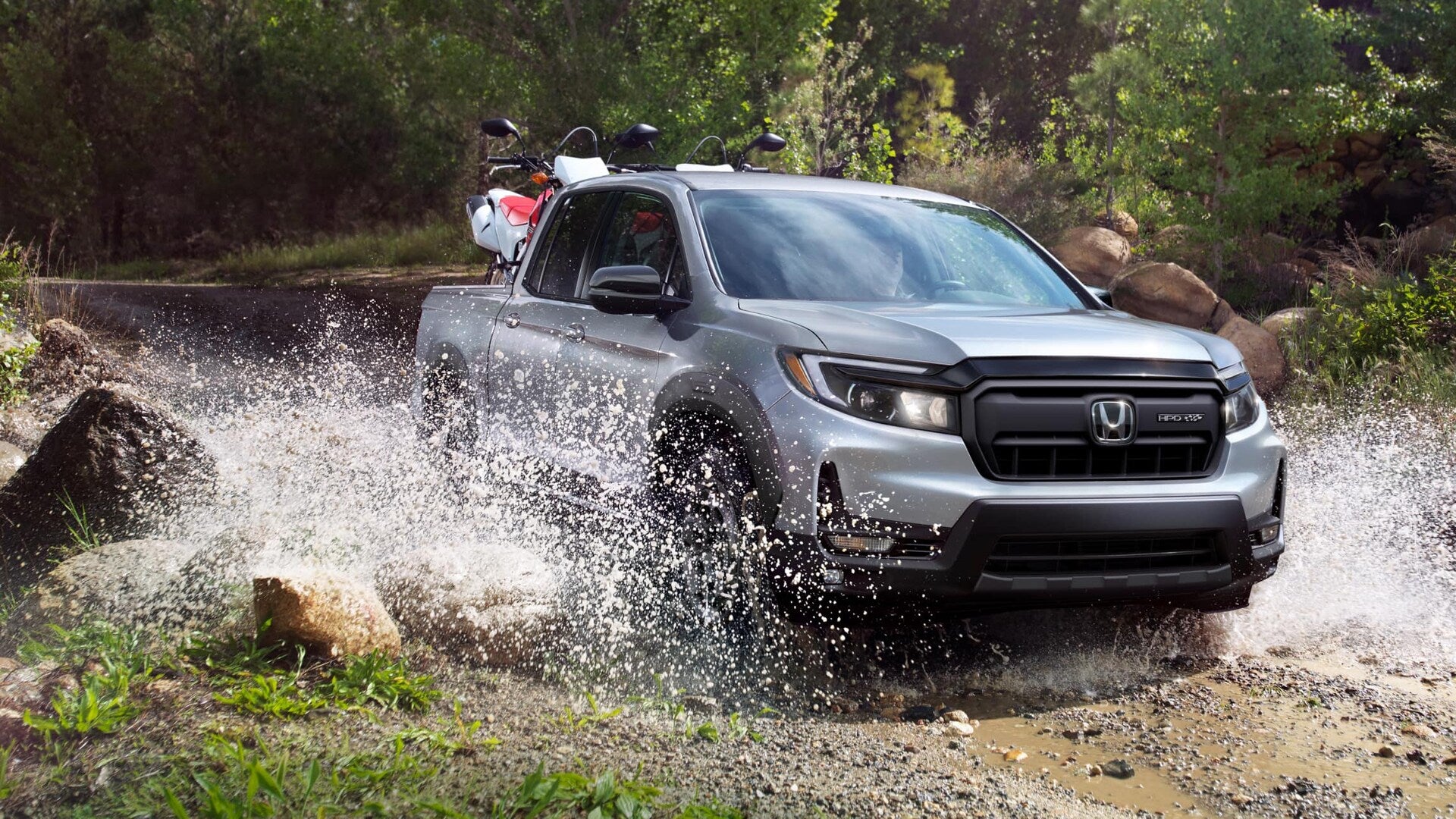 2025 Honda Ridgeline Sport AWD in Lunar Silver Metallic, driving across a small river.