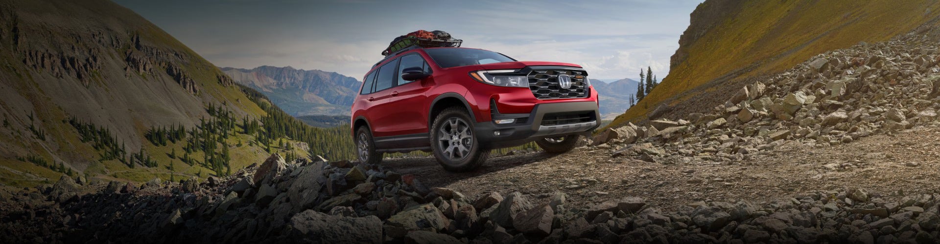 a red honda passport parked on a rocky terrain
