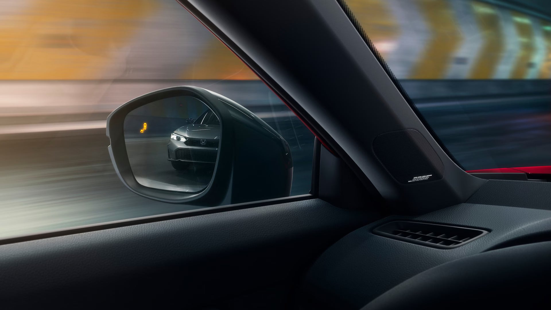 View of the 2025 Honda Civic from the side mirror with Blind Spot Information System indicator illuminated, highlighting safety features inside the car.