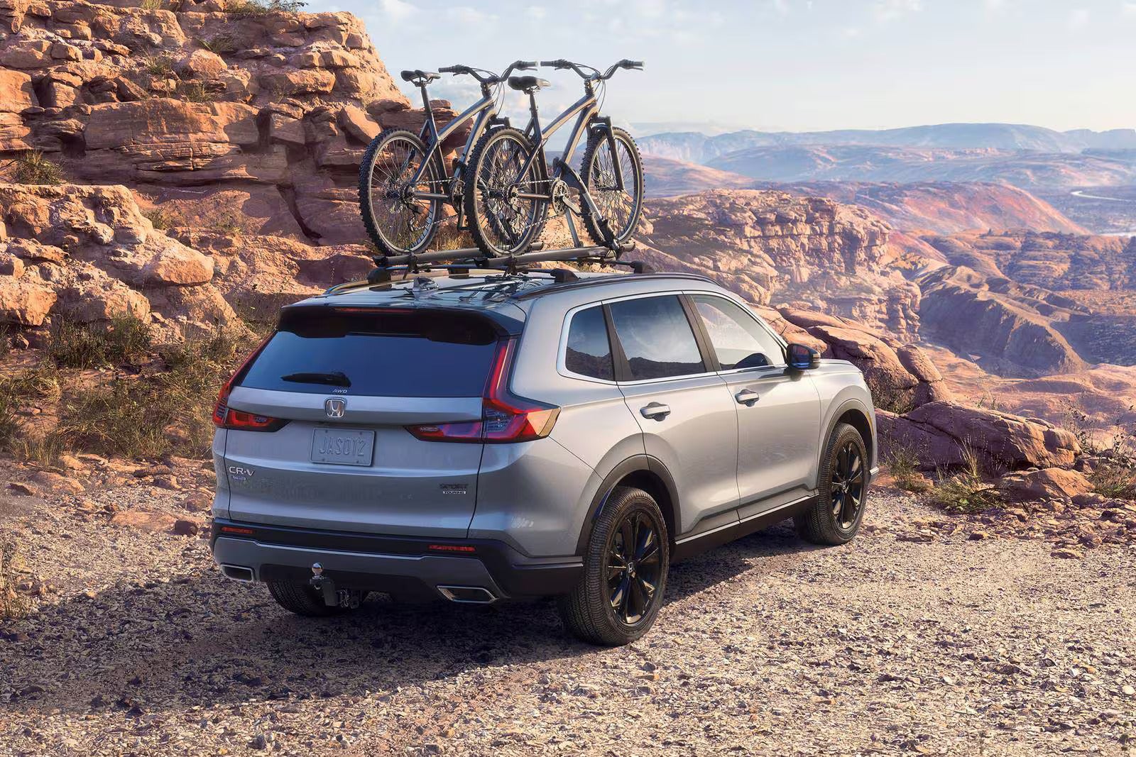 A gray suv parked with bikes on the roof.
