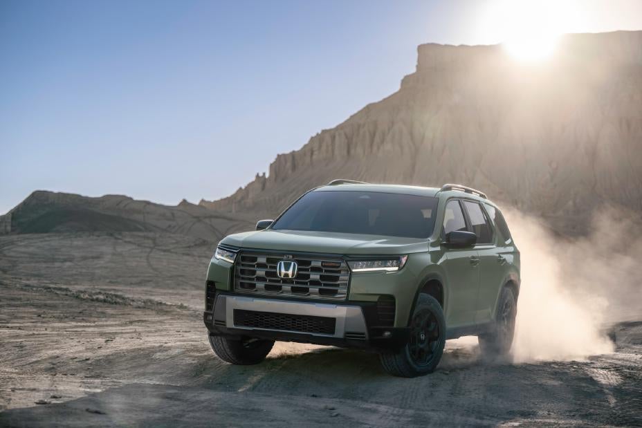 A green suv driving off-road.