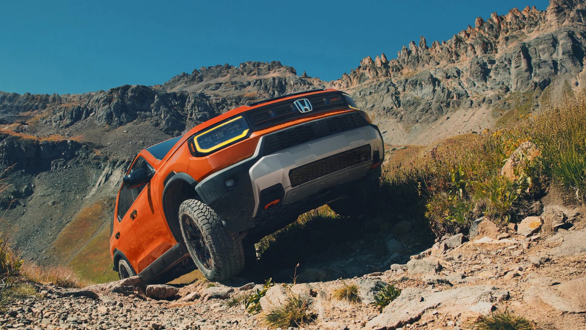 An orange suv driving up a hill.