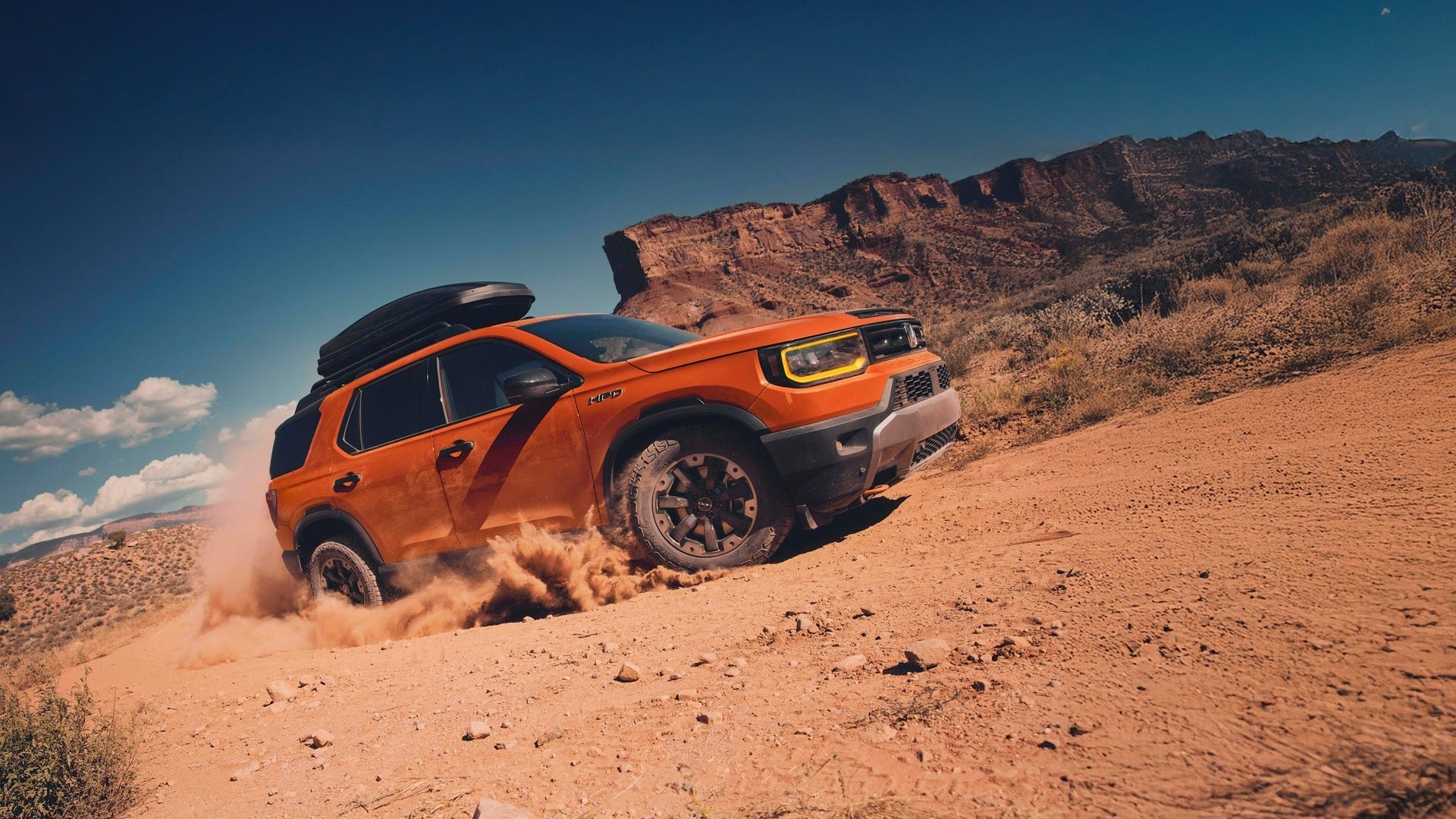A gray suv driving ona dirt road.
