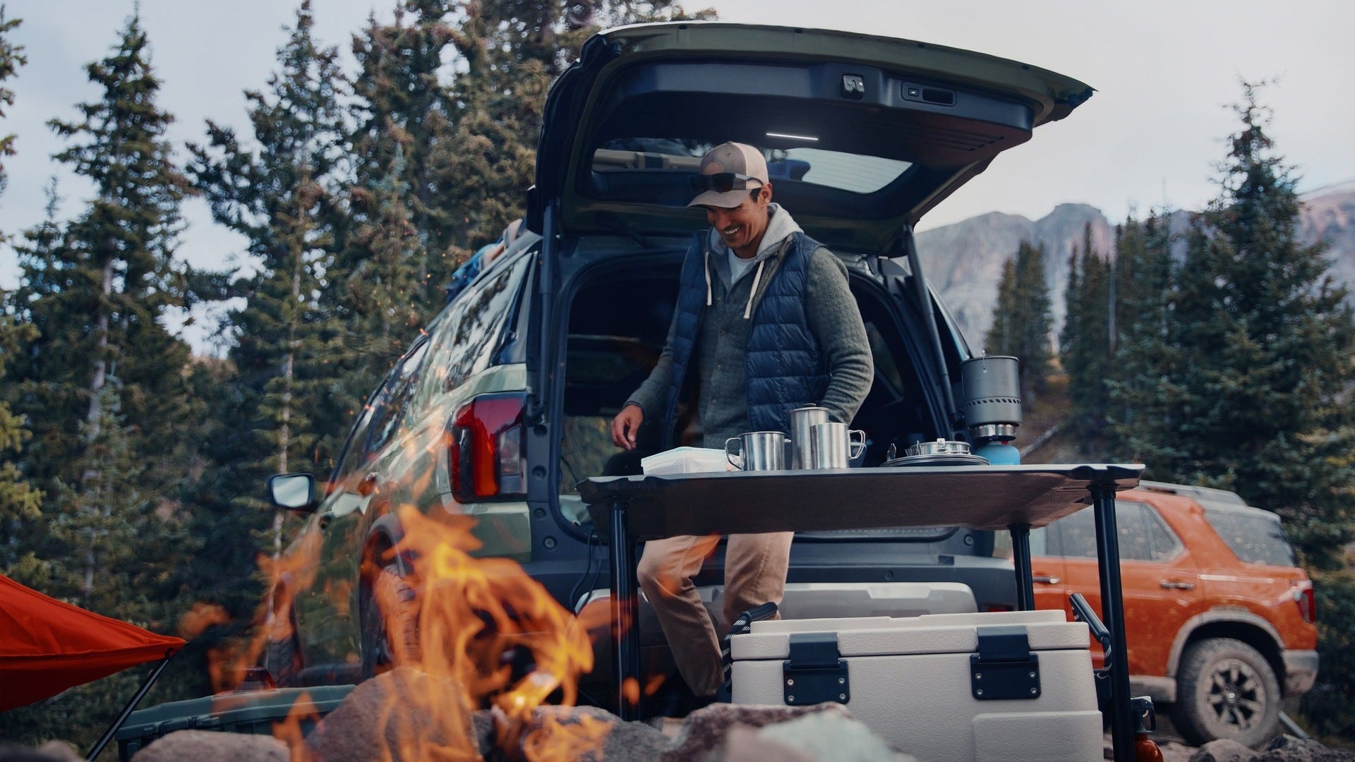 A man standing by a suv with the trunk open.
