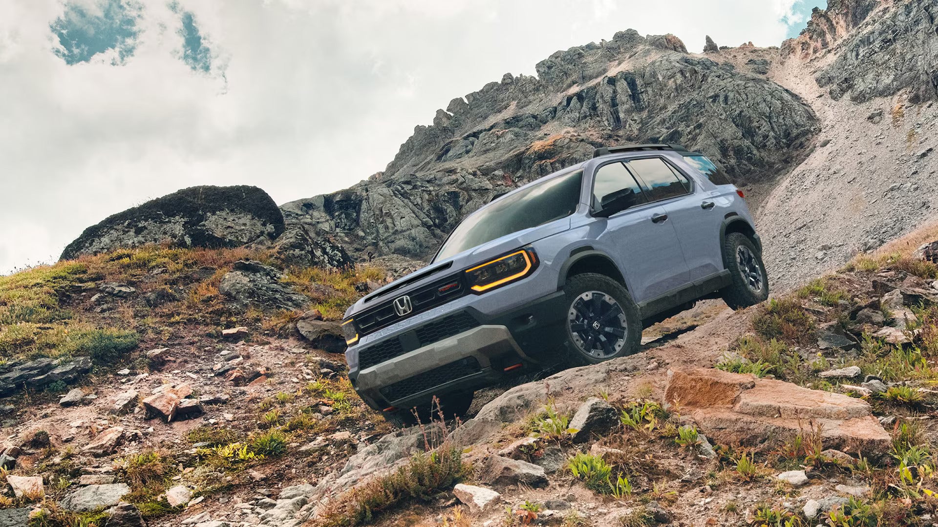A gray suv driving ona dirt road.