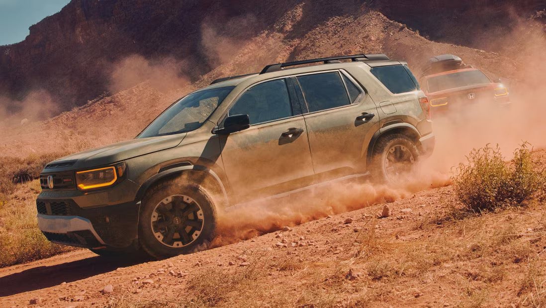 A green suv driving off-road.