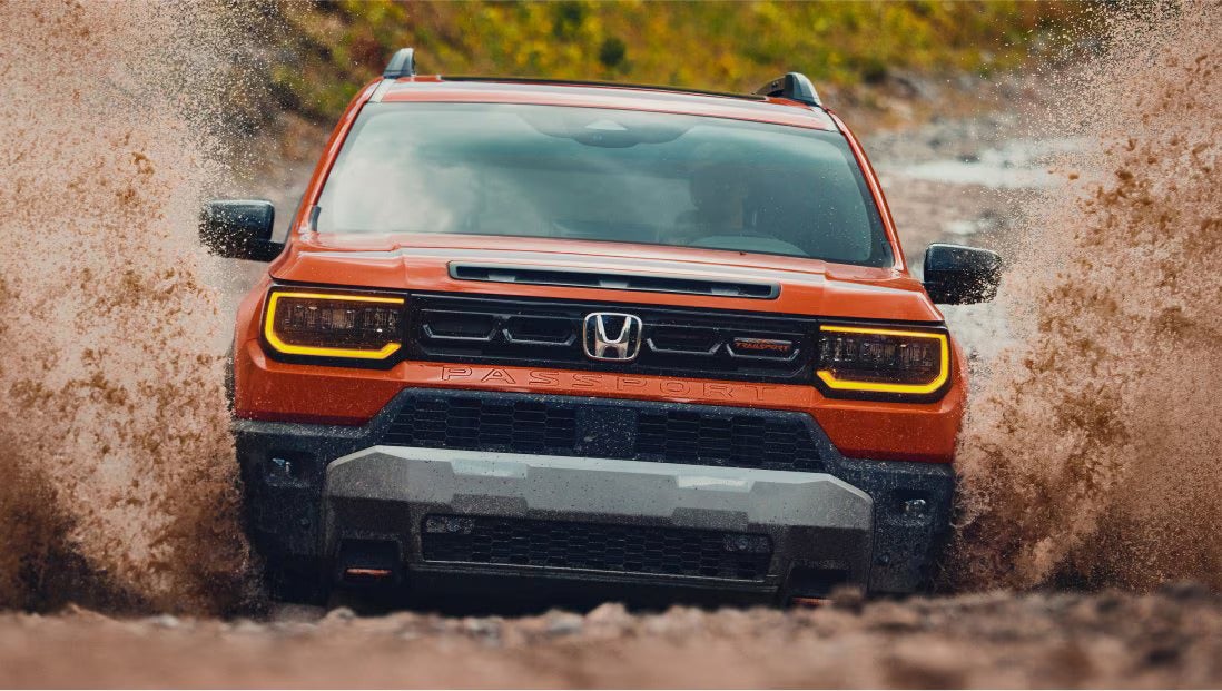 An orange suv driving through the mud.