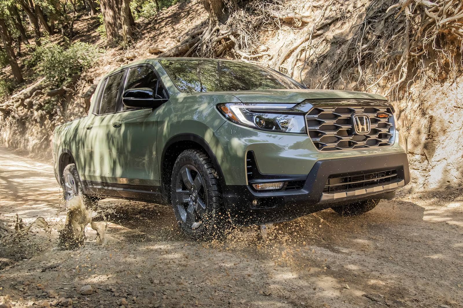 A green truck driving through mud.