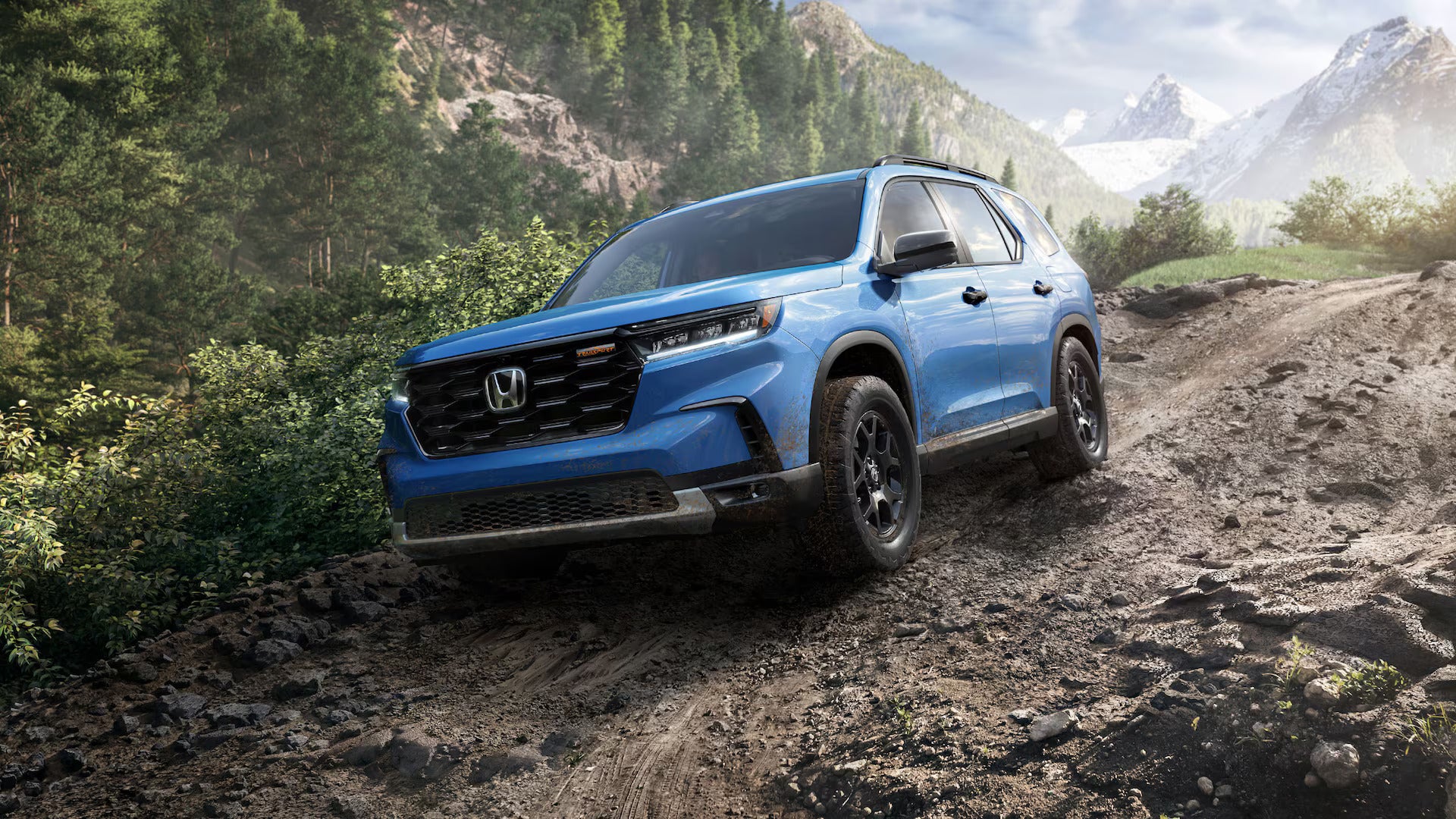 a blue suv driving on a muddy trail in the woods