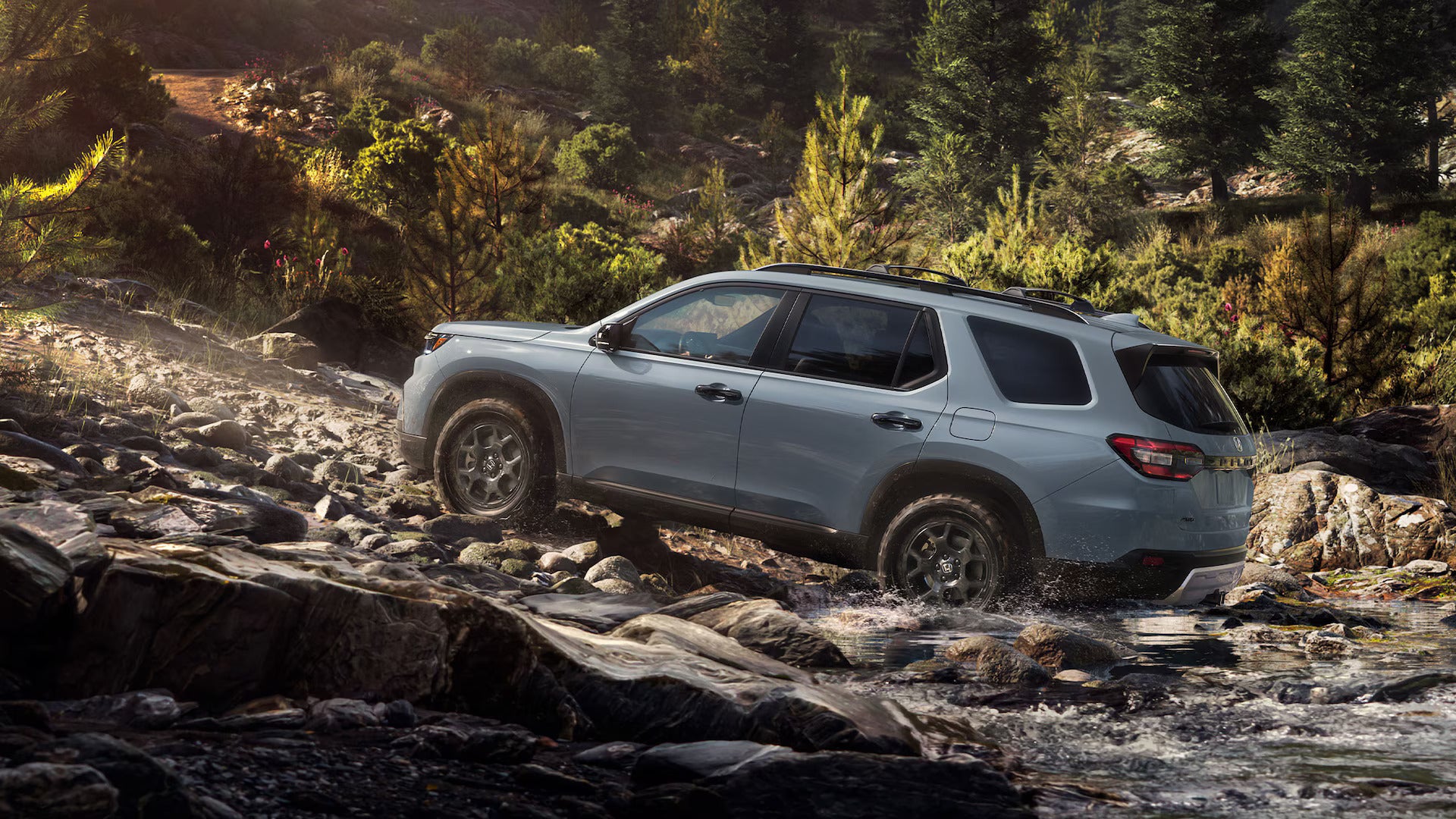 a gray suv driving on a rock bed in a ravine