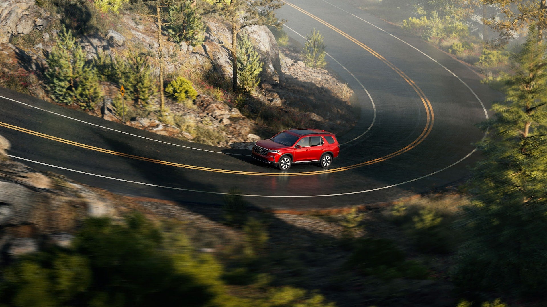 a red suv driving on a highway in the mountains
