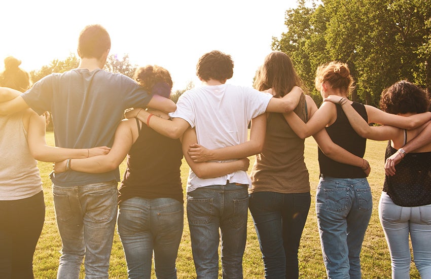A group of people with their arms around eachother.