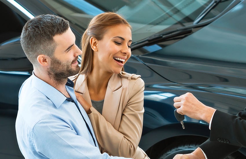 A man and woman getting the keys to a car.